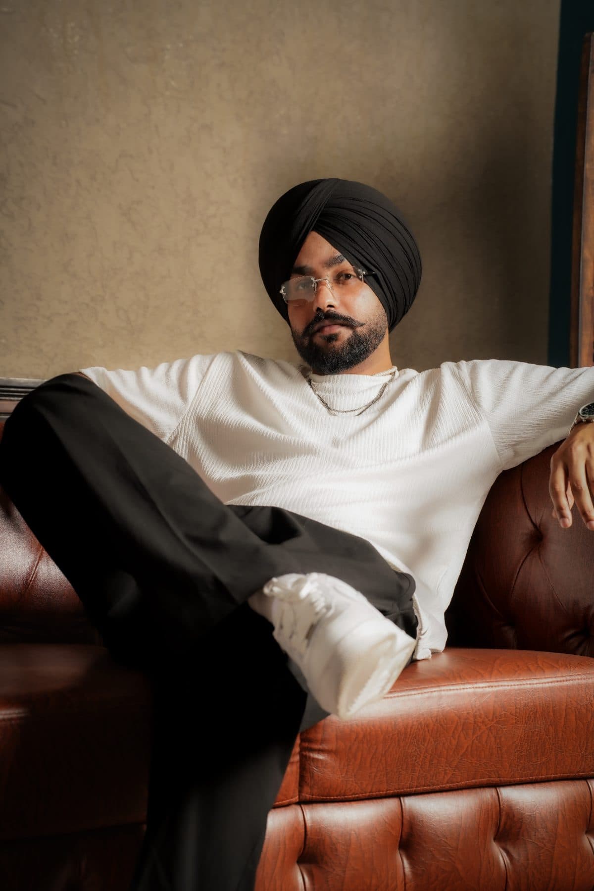 Zafar Sandhu on a cognac leather couch